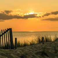 A tranquil beach scene at sunset with golden sands and calm waves, perfect for relaxation.
